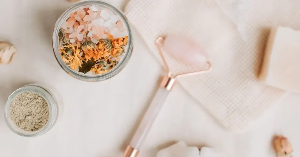 Aesthetic flat lay of a rose quartz face roller, herbal bath salts, and natural skincare products, perfect for a self-care glow-up routine.