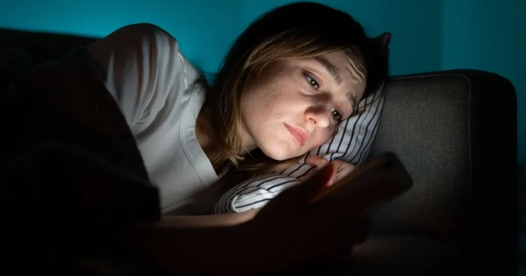 A lonely woman standing near a window, lost in thought, in a dimly lit room.
